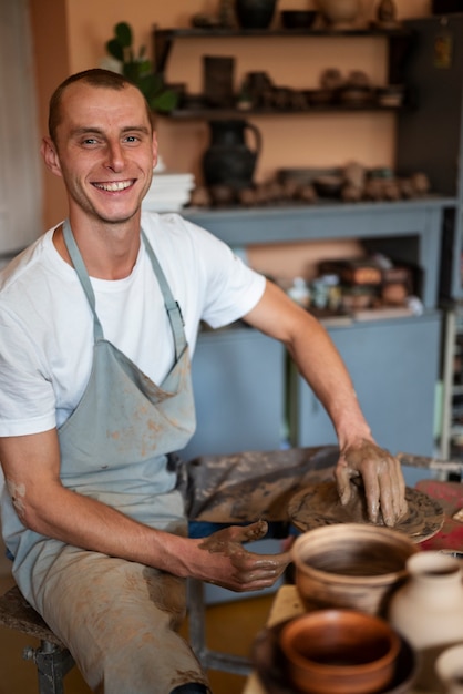 Hombre sonriente de tiro medio trabajando con arcilla