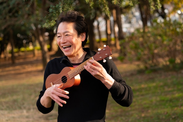 Foto hombre sonriente tocando ukelele tiro medio