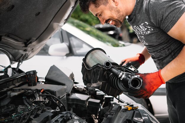 Foto hombre sonriente trabajando en un taller de reparación de automóviles