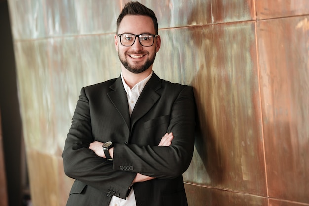 Hombre sonriente en traje cerca de la pared