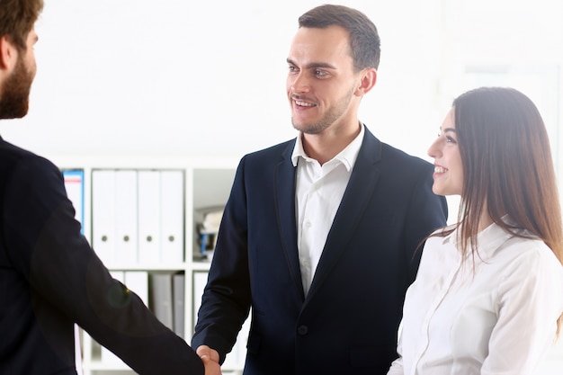 Foto hombre sonriente en traje se dan la mano como hola en la oficina