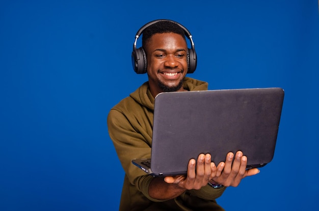 Hombre sonriente usando su portátil aislado sobre fondo azul.