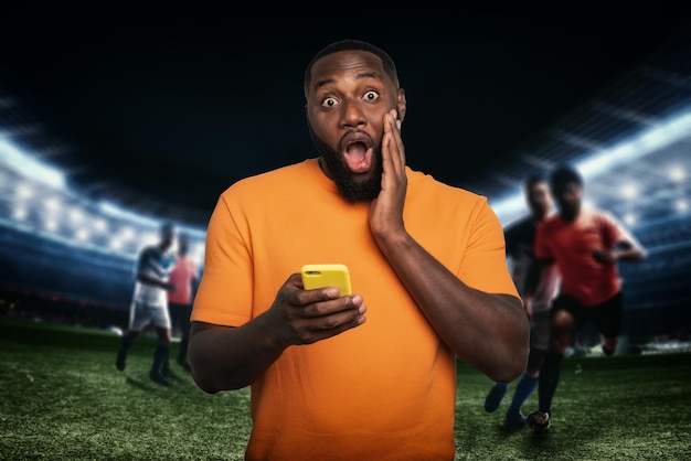 Hombre sorprendido por una acción de fútbol con celular en mano