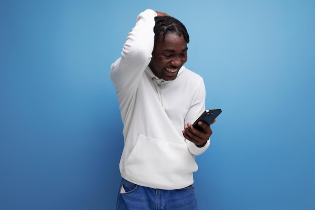 Hombre sorprendido alegre joven brunet hombre americano se comunica en el teléfono móvil