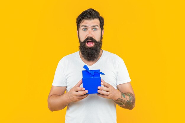 Hombre sorprendido con caja de regalo aislado en amarillo hombre con caja de regalo en estudio