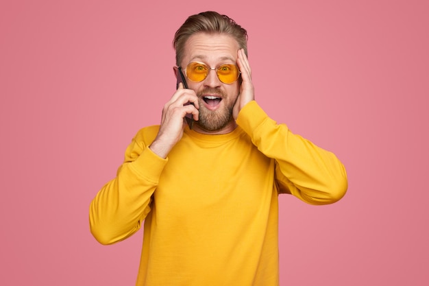 Hombre sorprendido hablando por teléfono inteligente en estudio