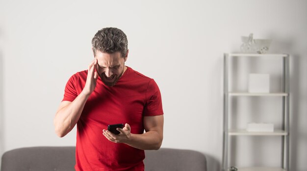 Hombre sorprendido leyendo mensaje en el teléfono en el interior de la oficina copia espacio malas noticias