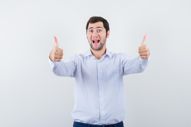 El hombre sorprendido muestra un gesto perfecto con los pulgares en el fondo blanco