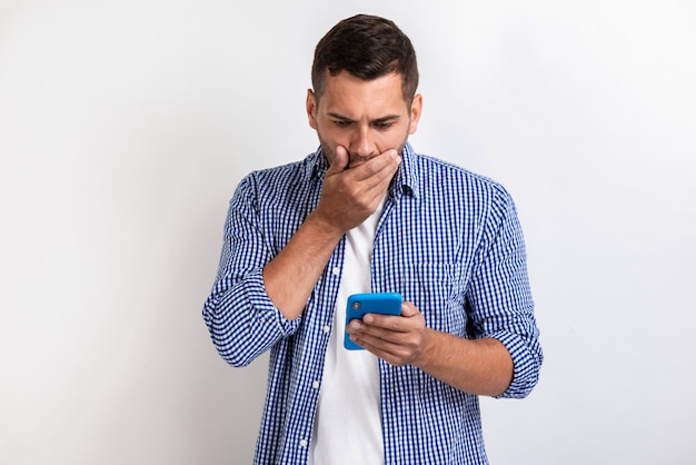 Hombre sorprendido que se coloca con un smartphone en sus manos y que mira la pantalla.