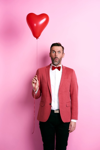 Foto hombre sorprendido que sostiene el globo en forma de corazón