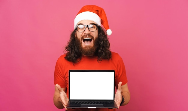Hombre sorprendido sostiene una computadora portátil abierta con pantalla en blanco para la oferta de Navidad