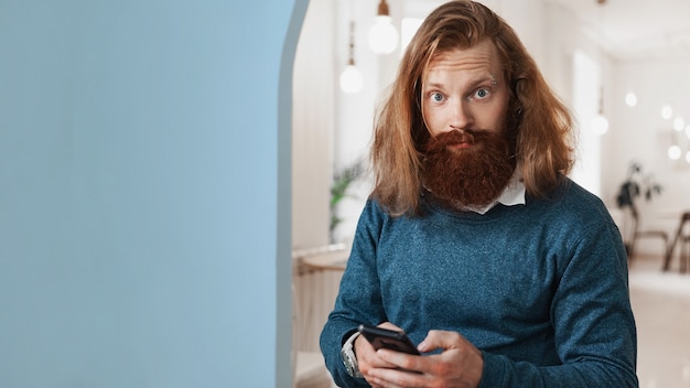 Hombre sorprendido con teléfono móvil mirando a la cámara