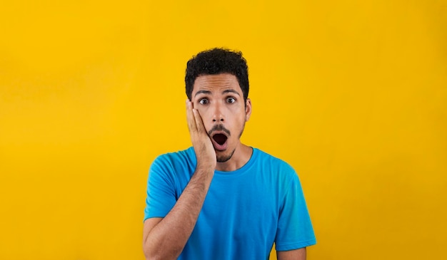 Hombre sorpresa aislado sobre fondo amarillo. Hombre negro guapo con camisa azul sobre amarillo.