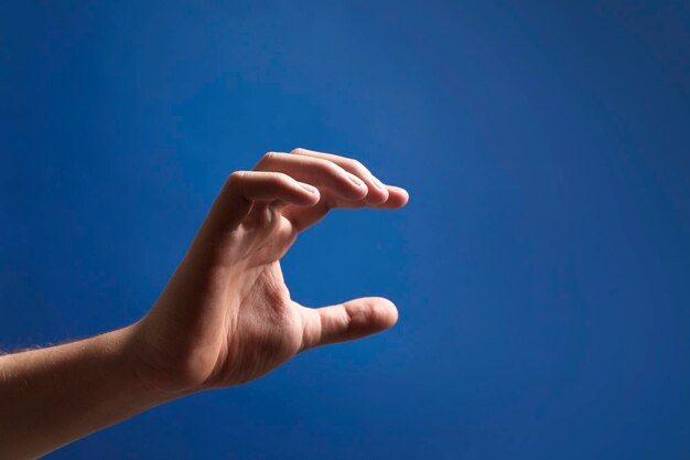Hombre sosteniendo algo en la mano en primer plano de fondo azul Espacio para texto