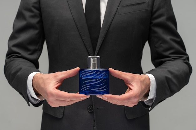 Foto hombre sosteniendo una botella de perfume fragancia de perfume de hombre perfume o botella de colonia y perfumería cosmética botella de colonia de aroma hombre sosteniendo colonia hombre de perfume masculino en un traje