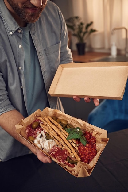 Foto el hombre está sosteniendo una caja ecológica de papel con comida en ella pepinos de carne y verduras