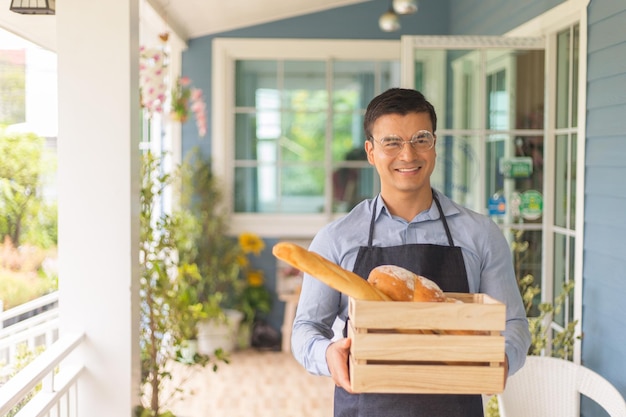 Hombre sosteniendo una caja de madera que contiene pan Concepto de propietario de negocio