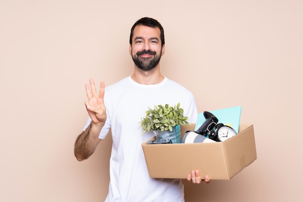 Hombre sosteniendo una caja y mudarse a un nuevo hogar feliz y contando tres con los dedos