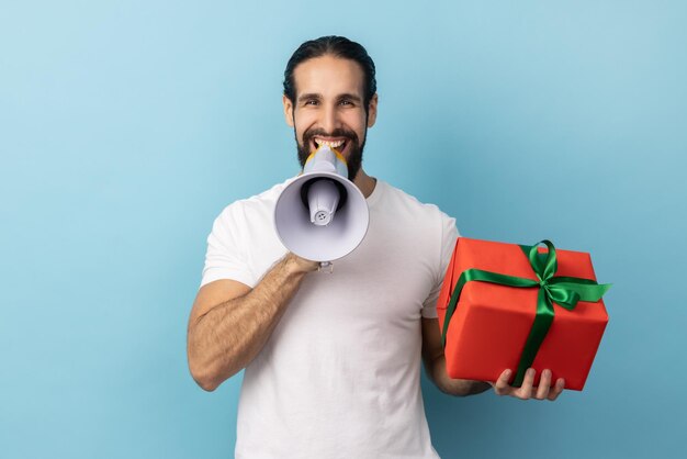 Hombre sosteniendo una caja de regalo roja y gritando en un megáfono haciendo un anuncio