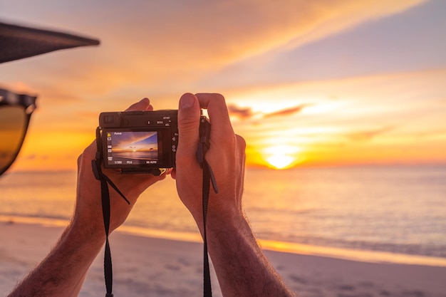 Hombre sosteniendo una cámara tomando fotos de la playa de verano Fotógrafos o viajeros usando una cámara digital