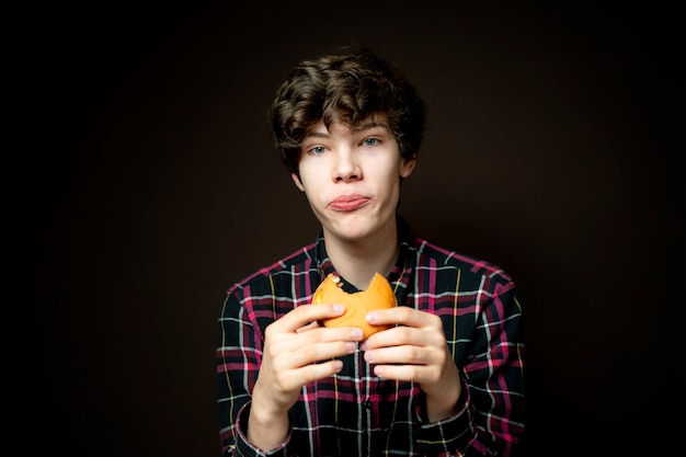 Hombre sosteniendo una hamburguesa con queso mordida y comiéndola apasionadamente f