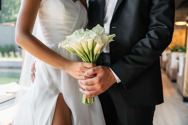 Foto el hombre está sosteniendo las manos de la novia en un abrazo una foto en primer plano de las novias ramo de lirios