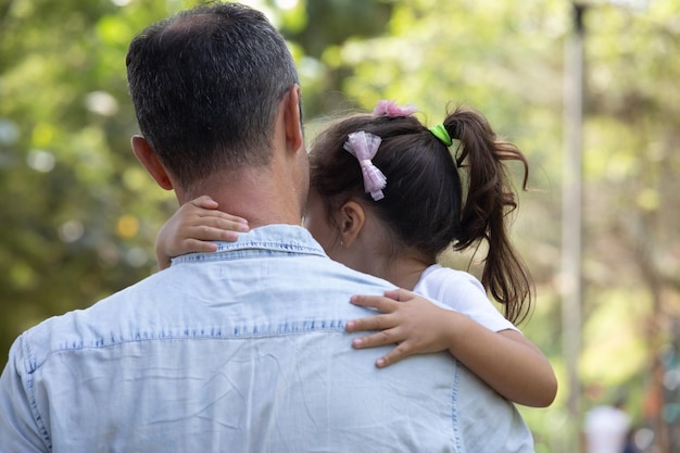 Foto un hombre sosteniendo a una niña con un lazo rosa en el cabello