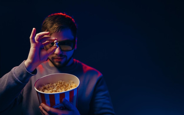 Hombre sosteniendo palomitas de maíz en gafas 3D Estrenos de proyecciones de películas Foto de póster con espacio para texto