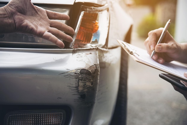Hombre sosteniendo un papel por el cliente que muestra un coche dañado