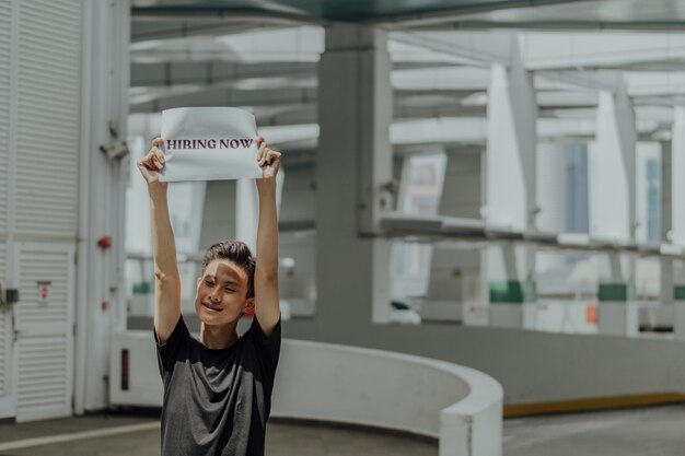 Foto hombre sosteniendo un papel con texto de pie al aire libre