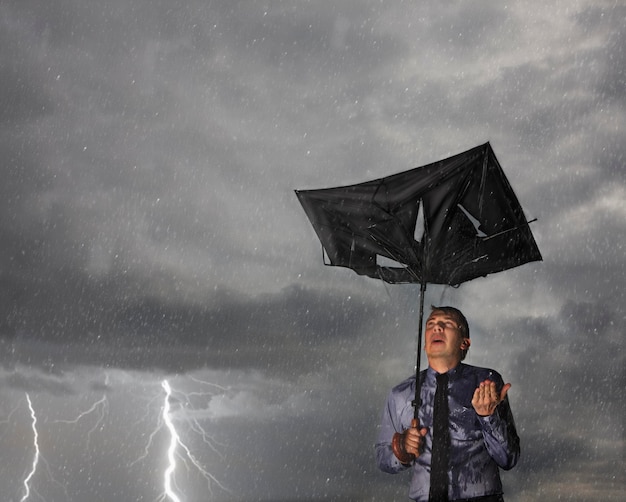 Foto hombre sosteniendo un paraguas dañado mientras está de pie durante la temporada de lluvias