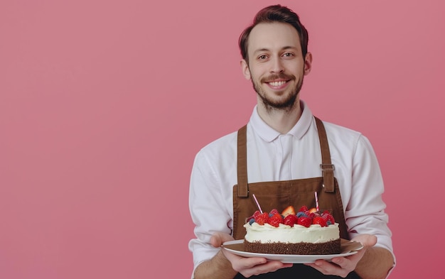 hombre sosteniendo pastel de cumpleaños en un fondo de color sólido panadería o concepto de feliz cumpleaños espacio para el texto