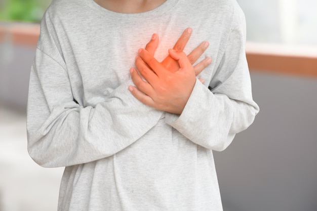 Hombre sosteniendo en el pecho tiene dolor de corazón causa de ataque al corazón o derrame cerebral con punto rojo al aire libre