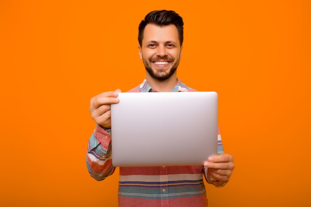 Foto hombre sosteniendo portátil y sonriendo a la cámara.