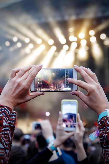 Hombre sosteniendo su teléfono inteligente y fotografiando un concierto