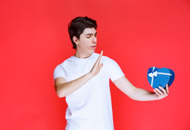 Hombre sosteniendo una tarjeta de regalo con forma de corazón y pensando.