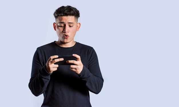 Hombre sosteniendo teléfono celular horizontalmente Chico jadeando y jugando juegos en su teléfono inteligente