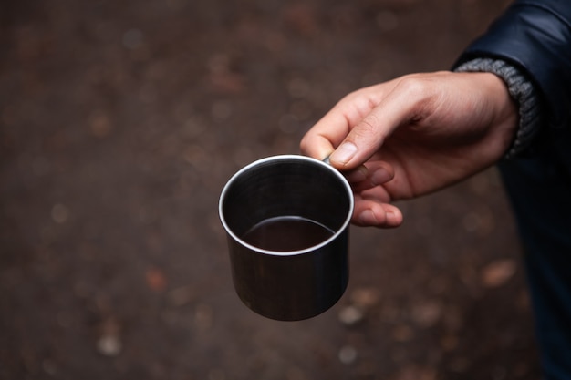 Un hombre sosteniendo un vaso en el bosque.