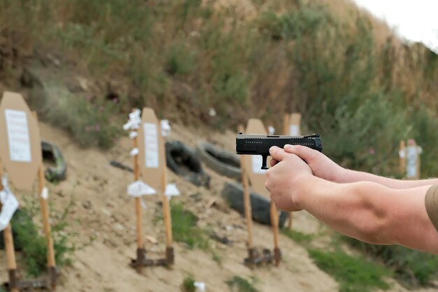 Un hombre sostiene un arma en sus manos ejercicios de tiro con pistola