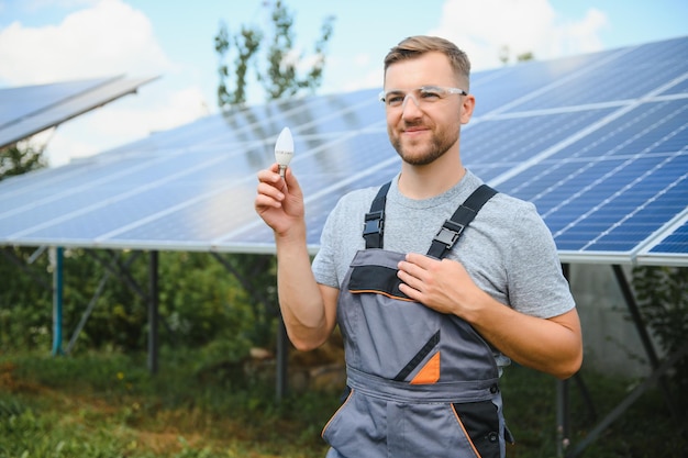 Un hombre sostiene una bombilla incandescente en su concepto de energía, el sol está limpio después del trabajo y reemplaza la energía que produce dióxido de carbono