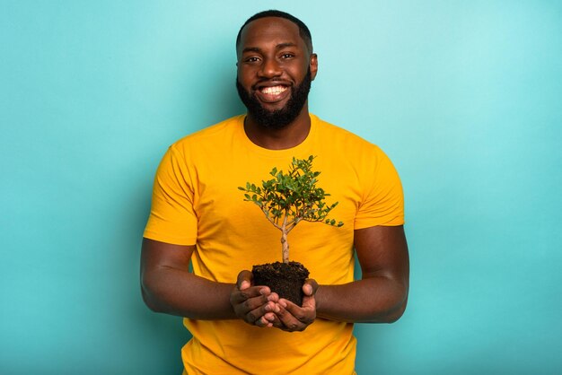 El hombre sostiene y cuida un árbol pequeño.