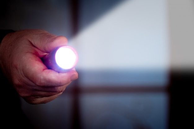 Un hombre sostiene una linterna en una habitación oscura. Penetración en la casa de otra persona.