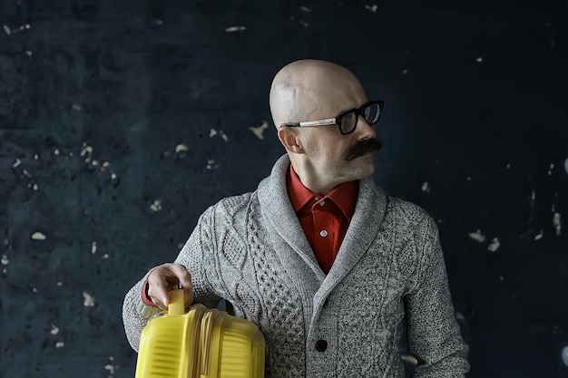 el hombre sostiene una maleta, concepto turístico, tipo de viaje bigotudo con gafas, tipo excéntrico