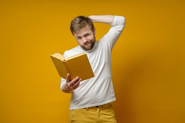 Foto el hombre sostiene en las manos un libro que ha leído hasta la mitad y ahora está experimentando contradicciones