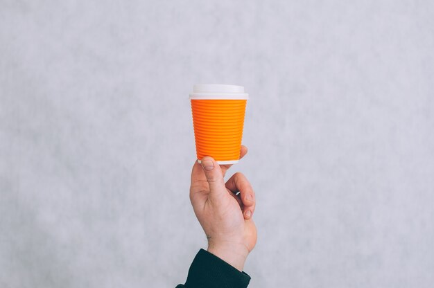 Un hombre sostiene una maqueta de una taza de papel para café y té en una luz.