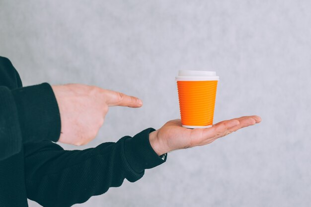 Un hombre sostiene una maqueta de una taza de papel para café y té en una luz.