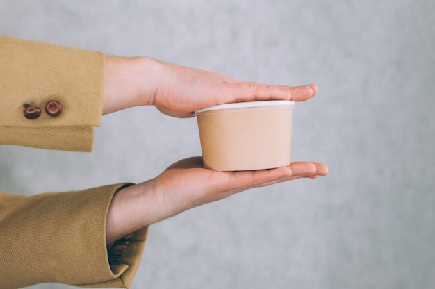 Un hombre sostiene una maqueta de un vaso de papel para sopa, café y té en una luz.