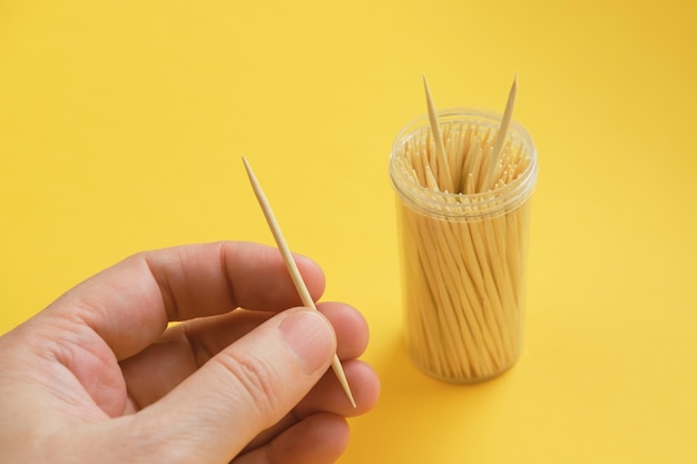 El hombre sostiene un palillo de madera en sus manos sobre un fondo amarillo