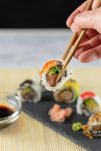 El hombre sostiene palillos de sushi sobre el resto del plato de sushi Enfoque selectivo