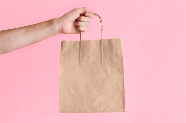 Hombre sostiene un paquete de artesanía en un fondo de color espacio en blanco en una bolsa de papel marrón espacio de copia
